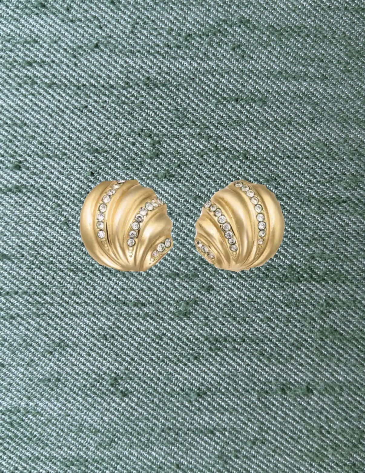 Pair of matt gold swirl earrings set with crystals on green silk