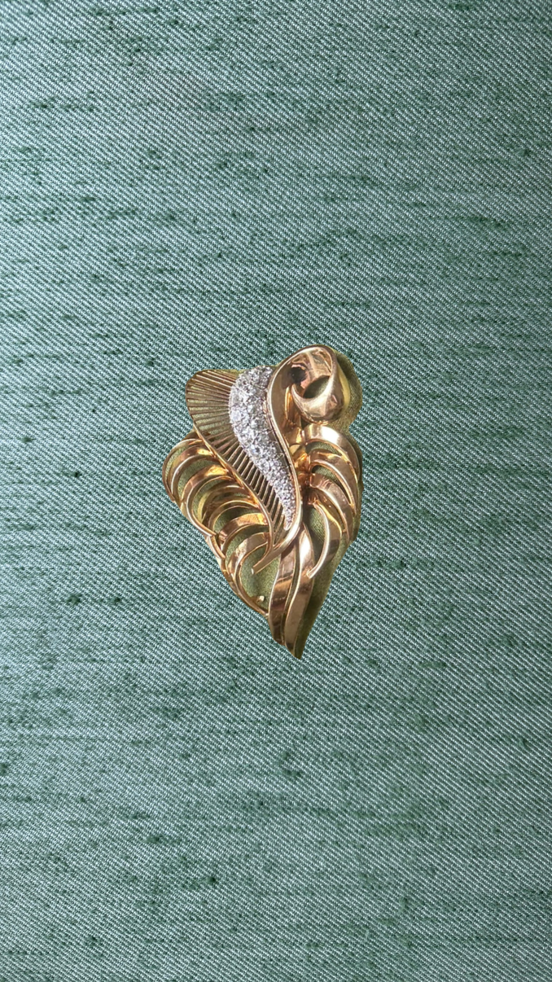 Vintage gold and diamond leaf brooch on green silk